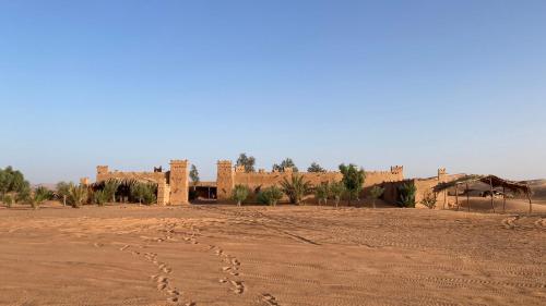 an old building in the desert with footprints in the dirt at Auberge Dinosaur Kem Kem in Tafraoute Sidi Ali