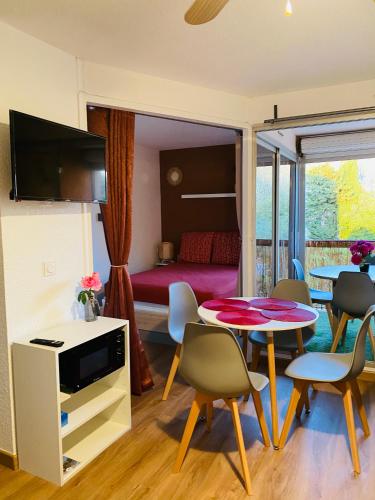 un salon avec une table et des chaises et une chambre dans l'établissement Agréable appartement aux Capellans avec loggia, WIFI et parking, à Saint-Cyprien