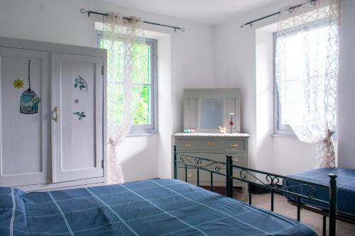 a bedroom with a bed and a dresser and windows at Casa Bertulla in Cabella Ligure