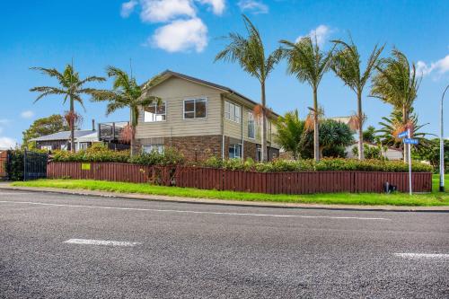 a house with palm trees on the side of the road at Sandy Feet Retreat close to Beach in Clarks Beach