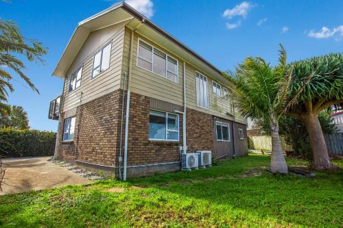a house with a palm tree in front of it at Sandy Feet Retreat close to Beach in Clarks Beach