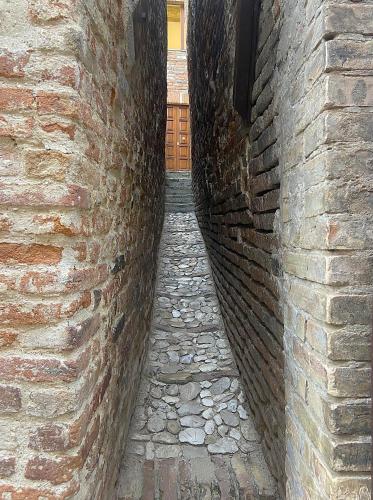 an alley with a brick wall next to a building at La Casa Nel Bosco in Ripatransone