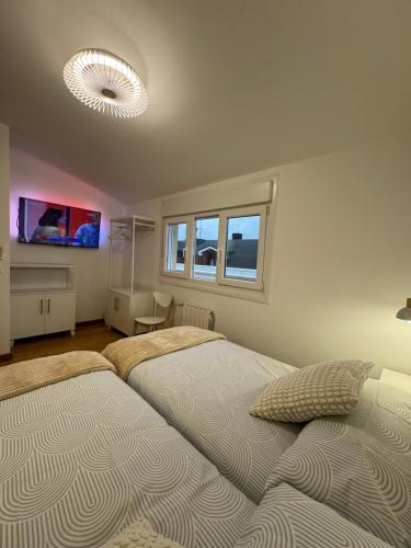 a bedroom with two beds and a tv and windows at Apartamentos Olga Cantabria 2 in Polanco