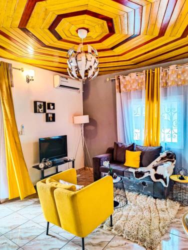 sala de estar con muebles de color amarillo y techo artesonado en Studio Yellow yassa Ari Dom City, en Douala