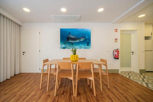 a dining room with a table and a shark painting on the wall at Azimute 1 - T2 Moderno Centro Histórico Angra in Angra do Heroísmo