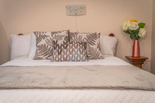 a bed with pillows and a vase of flowers on it at UKUKU Hostel in Quito