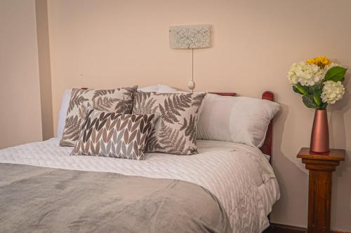 a bedroom with a bed with pillows and a vase of flowers at UKUKU Hostel in Quito