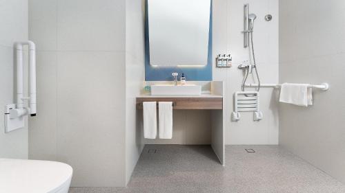 a bathroom with a sink and a mirror at Holiday Inn Express Qingdao Shibei by IHG in Qingdao