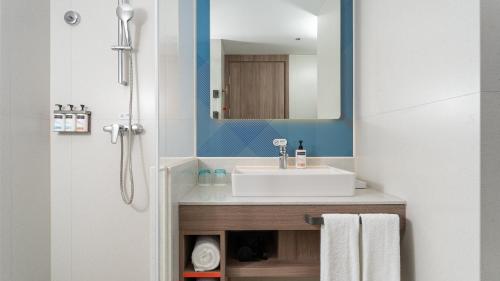 a bathroom with a sink and a mirror at Holiday Inn Express Qingdao Shibei by IHG in Qingdao