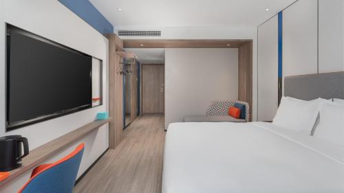 a bedroom with a bed and a flat screen tv at Holiday Inn Express Qingdao Shibei by IHG in Qingdao