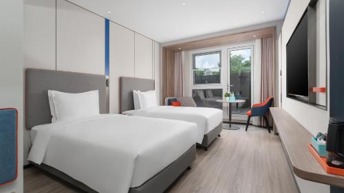a hotel room with two beds and a table at Holiday Inn Express Qingdao Shibei by IHG in Qingdao