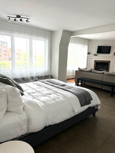 a white bedroom with a large bed and a couch at Auberge des Cantons in Magog-Orford