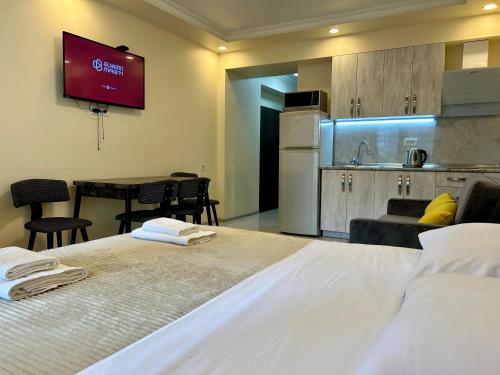 a bedroom with a large white bed and a kitchen at Real Beach Tower in Batumi