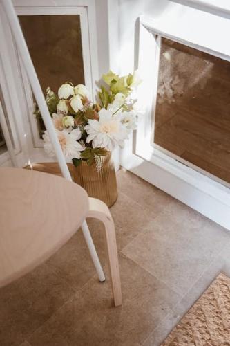 a white chair and a vase of flowers next to a window at Pablo Apartment in Cesis in Cēsis