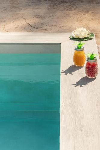 two vases with flowers on a table next to water at Petros Giatras - Rooms in Zakynthos Town