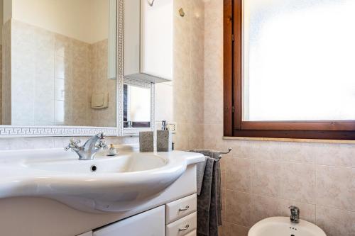 a bathroom with a sink and a mirror and a toilet at Casa vacanze della Corte in Sestu
