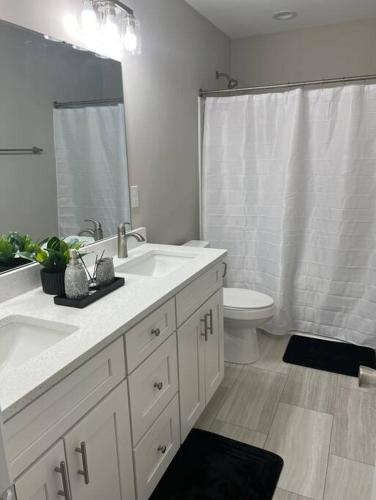 シャーロットにあるRockwell Retreatの洗面台2つとトイレ付きの白いバスルーム