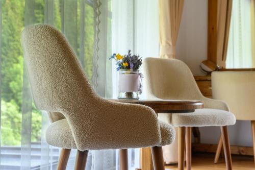 two chairs sitting next to a table with a vase of flowers at Casa Baciu Colacu in Fundu Moldovei