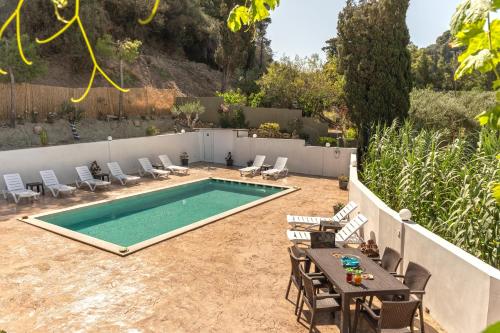 a swimming pool in a yard with chairs and a table at Petros Giatras - Rooms in Zakynthos Town