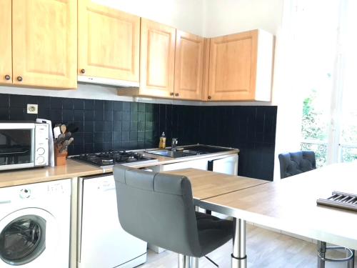 une cuisine avec des armoires en bois et une table avec des chaises dans l'établissement RUE DE LA PAIX - Hypercentre - Thermes - Calme, à Vichy