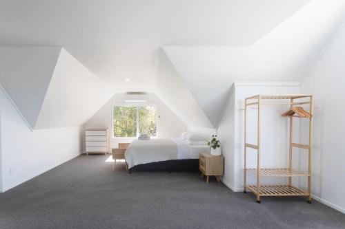 une chambre blanche avec un lit et une fenêtre dans l'établissement Okere Lakehouse Retreat, à Okere Falls