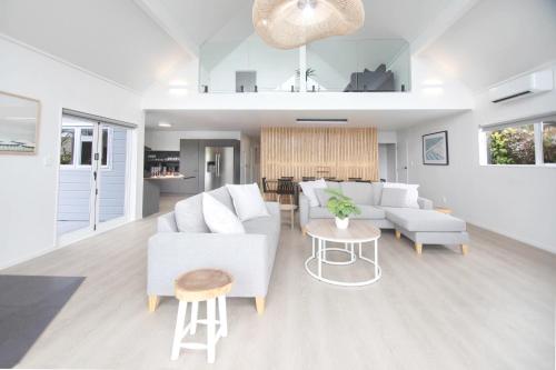 un salon avec des meubles blancs et une table dans l'établissement Okere Lakehouse Retreat, à Okere Falls