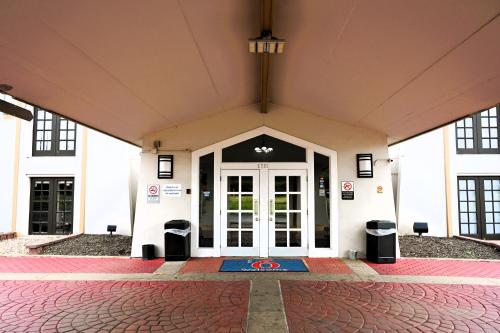 a front door of a white building with two trash cans at Motel 6-Hazelwood, MO in Hazelwood