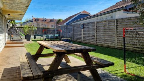 - une table de pique-nique en bois dans une cour avec une aire de jeux dans l'établissement La maison du Lhéris, à Bagnères-de-Bigorre