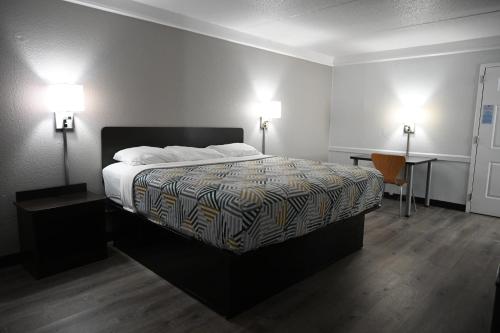 a bedroom with a bed with two lamps and a desk at Motel 6-Hazelwood, MO in Hazelwood