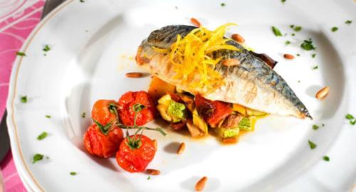 a white plate with a fish with cheese and tomatoes at Atilius Hotel & Suites in Riccione