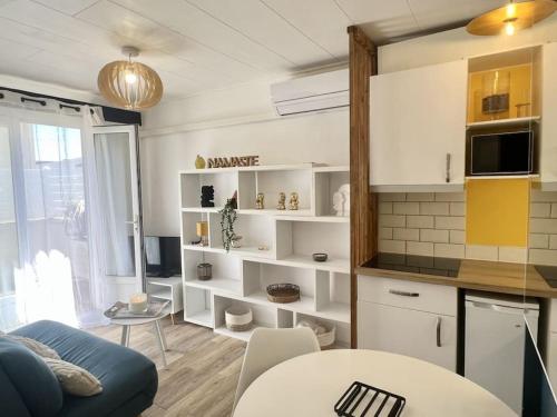 ein Wohnzimmer mit einer blauen Couch und einer Küche in der Unterkunft Le Tropico - Clim - Terrasse - Proche Polygone in Béziers