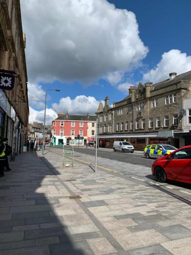 Una calle con edificios y un coche rojo aparcado en la calle. en Twin room close to Royal Troon free parking, en Irvine