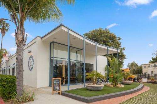 a white building with large windows and a palm tree at ITH Santa Barbara Surf Hostel in Santa Barbara