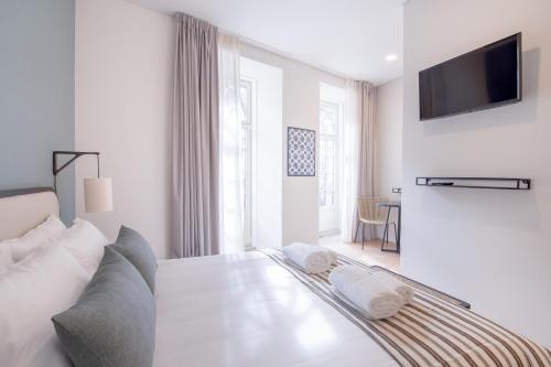 Habitación blanca con cama y TV de pantalla plana. en VC Heritage Ribeira Porto, en Oporto