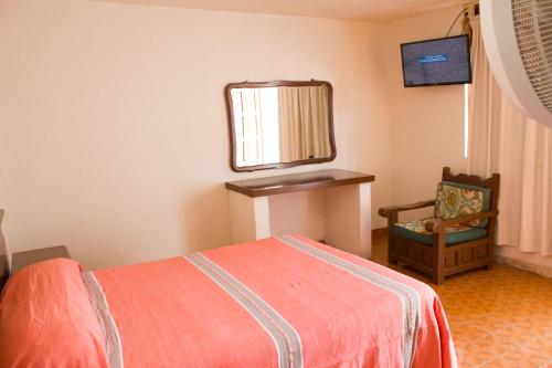 a bedroom with a bed and a mirror and a chair at Hotel Avenida Ixmiquilpan in Ixmiquilpan