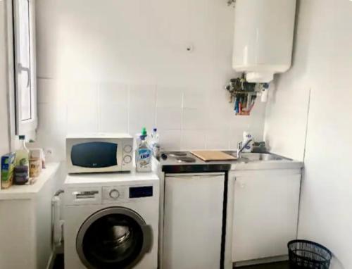 une cuisine avec un lave-linge et un micro-ondes dans l'établissement Beau studio gare, à Montataire