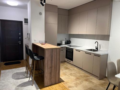 a kitchen with white cabinets and a counter with chairs at Skyline Serenity Apartment in Prizren