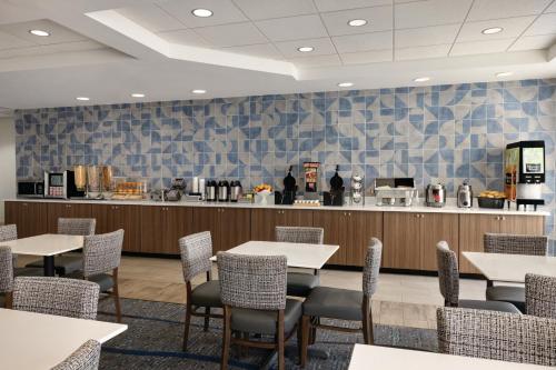 a restaurant with tables and chairs and a counter at La Quinta by Wyndham Springfield Airport Plaza in Springfield