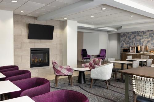 a waiting room with purple chairs and a fireplace at La Quinta by Wyndham Springfield Airport Plaza in Springfield
