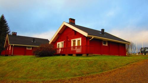 a red house sitting on top of a green field at Holiday Village Kuukiuru in Vuostimo