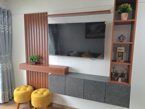 a tv on a wall with two yellow stools at Departamento Pardo Miraflores in Lima