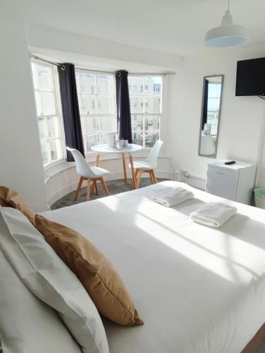 a white bed with two chairs and a table in a room at Central Wave in Brighton & Hove