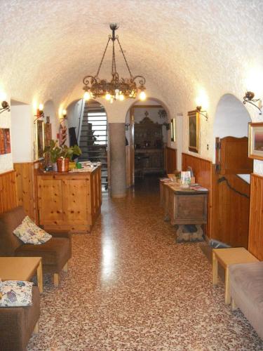 a living room with a chandelier and a room with tables at Hotel Gufo in Bormio