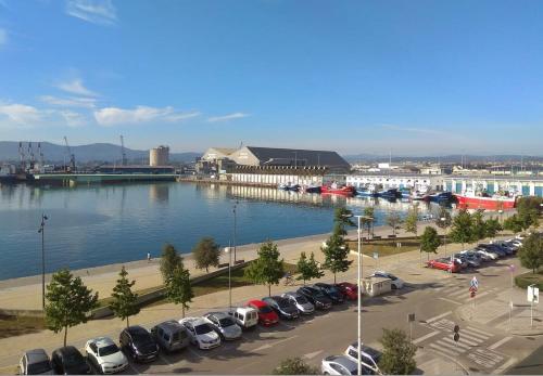 Un estacionamiento con autos estacionados al lado de un cuerpo de agua. en Sailor Home Apartamento con vistas al puerto de Santander, en Santander
