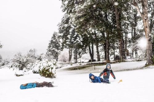 two people are laying in the snow at CASA del LAGO Bariloche in San Carlos de Bariloche