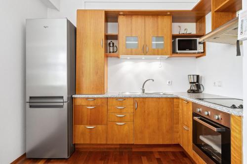 a kitchen with wooden cabinets and a stainless steel refrigerator at River Apartments in Selfoss