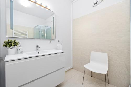 a white bathroom with a sink and a chair at River Apartments in Selfoss