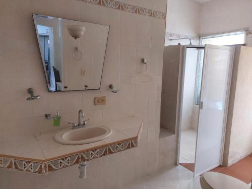 a bathroom with a sink and a shower with a mirror at Serenity Home Hospedaje con confort y seguridad in Mérida