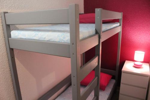 Ce lit se trouve dans un dortoir doté de 2 lits superposés et d'un mur rouge. dans l'établissement Joli studio terrasse avec piscine et parking, à Saint-Cyprien