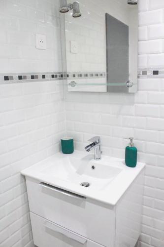 une salle de bain blanche avec un lavabo et un miroir dans l'établissement Joli studio terrasse avec piscine et parking, à Saint-Cyprien